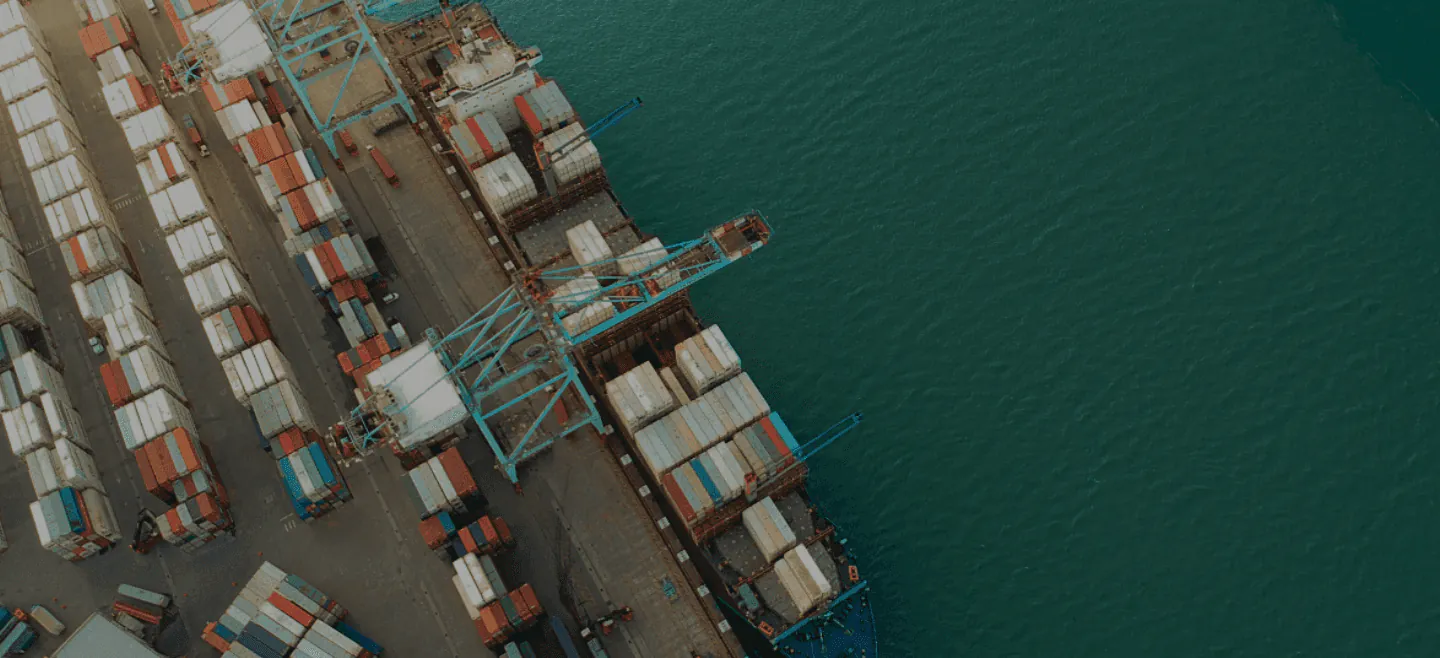 A container vessel being worked alongside a stacked terminal yard